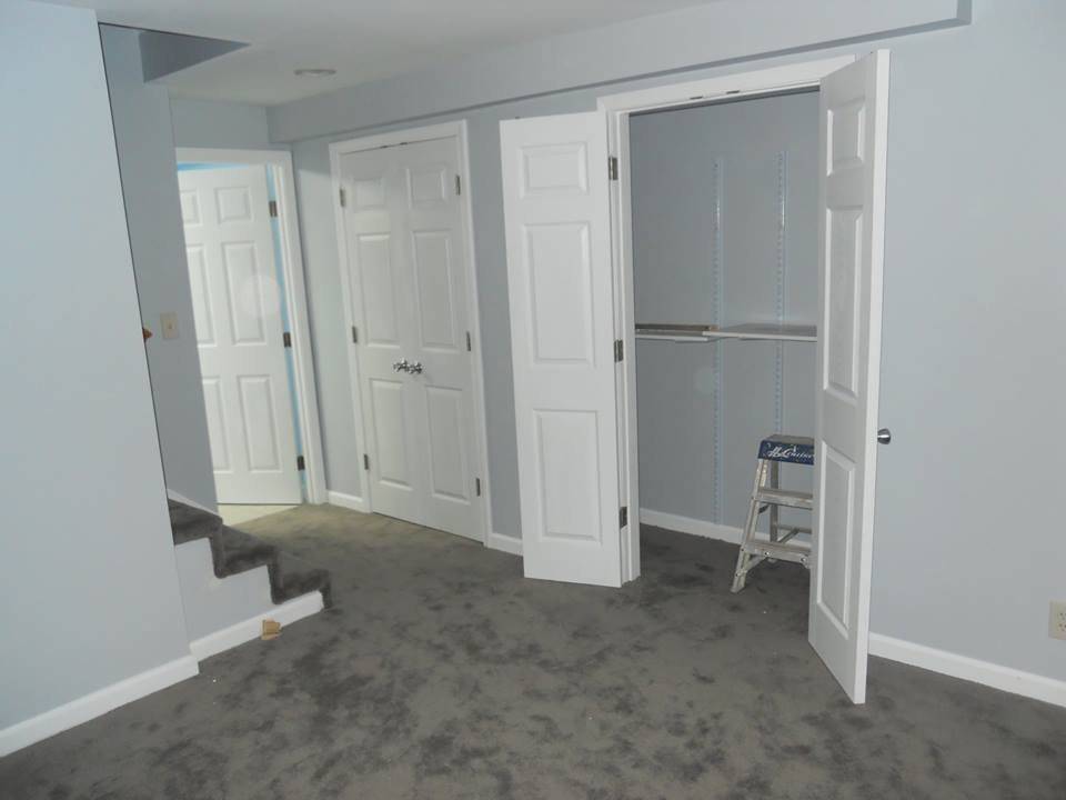 The same basement finished — painted walls, carpet laid, six-panel doors hung, and a closet fitted with shelving