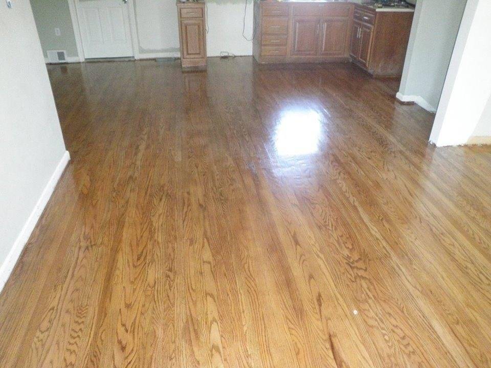 Refinished oak hardwood flooring running through an open living area into a kitchen