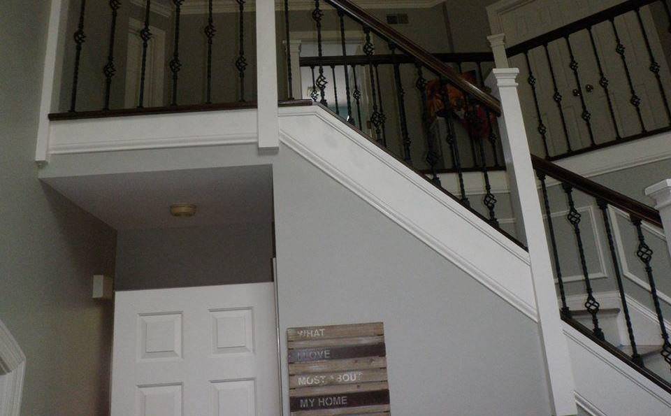 An upper landing with matching wrought iron balusters, stained handrail, and panelled wainscoting